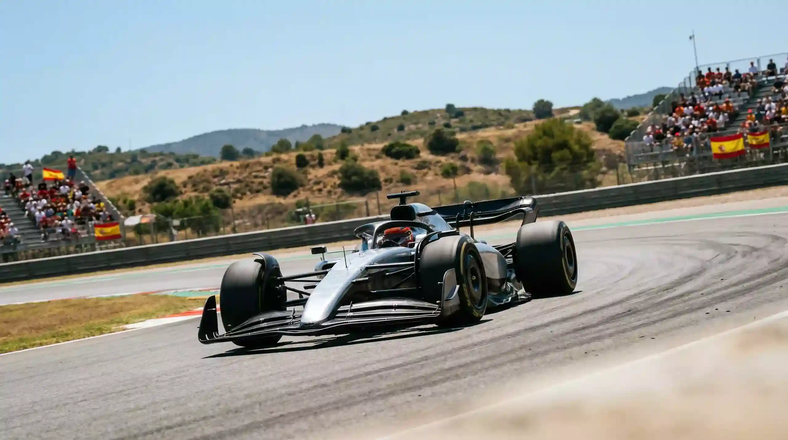 Monoplaza de Fórmula 1 acelerando en el circuito de Barcelona-Catalunya bajo el sol español