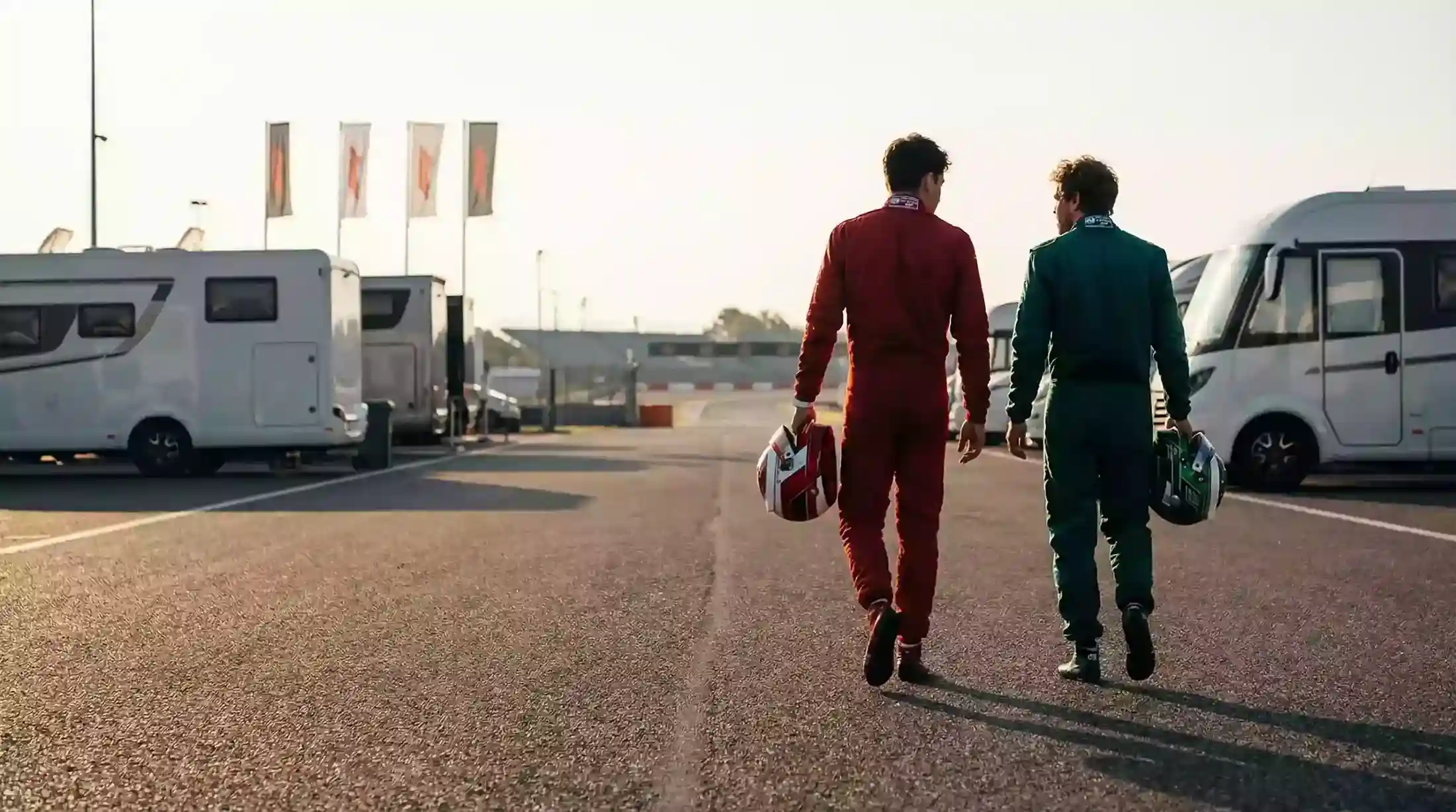 Dos pilotos de Fórmula 1 con casco bajo el brazo en el paddock antes de una carrera